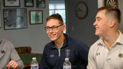 Rob Rucki ’24, center, and George Bednar ’23, right, enjoy a visit to the Montalbano home on a recent weeknight. They are in Notre Dame’s Naval ROTC program, or NROTC, and will be commissioned as Marine Corps officers. Rucki and Bednar are quoted in this article. (Photos by Matt Cashore/University of Notre Dame)